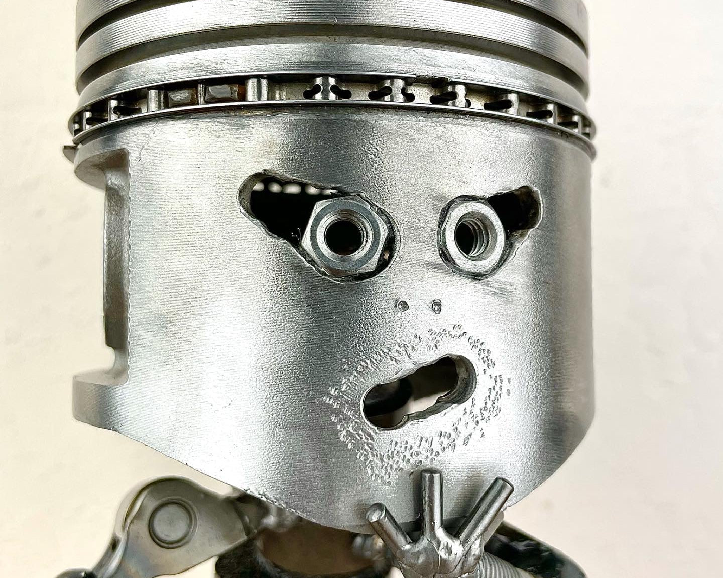 Metallic piston with a face on a beige background