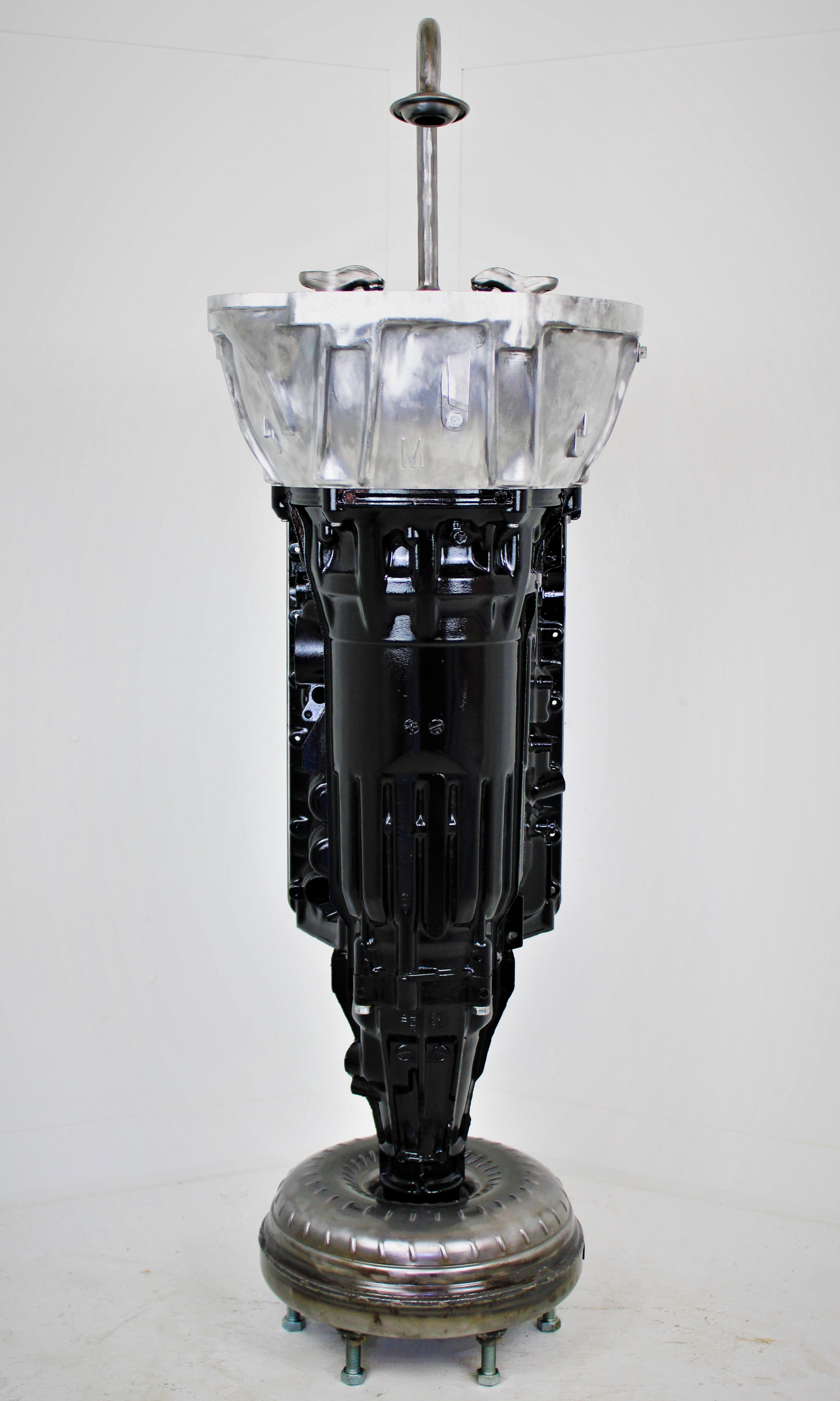 Vintage engine block repurposed as a lamp on a white background