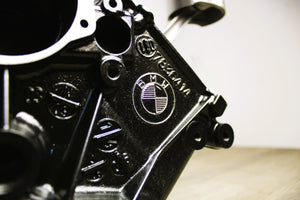 A close-up of the BMW logo on a BMW M Series V10 engine block coffee table painted in the BMW M-Power color scheme without its glass top.