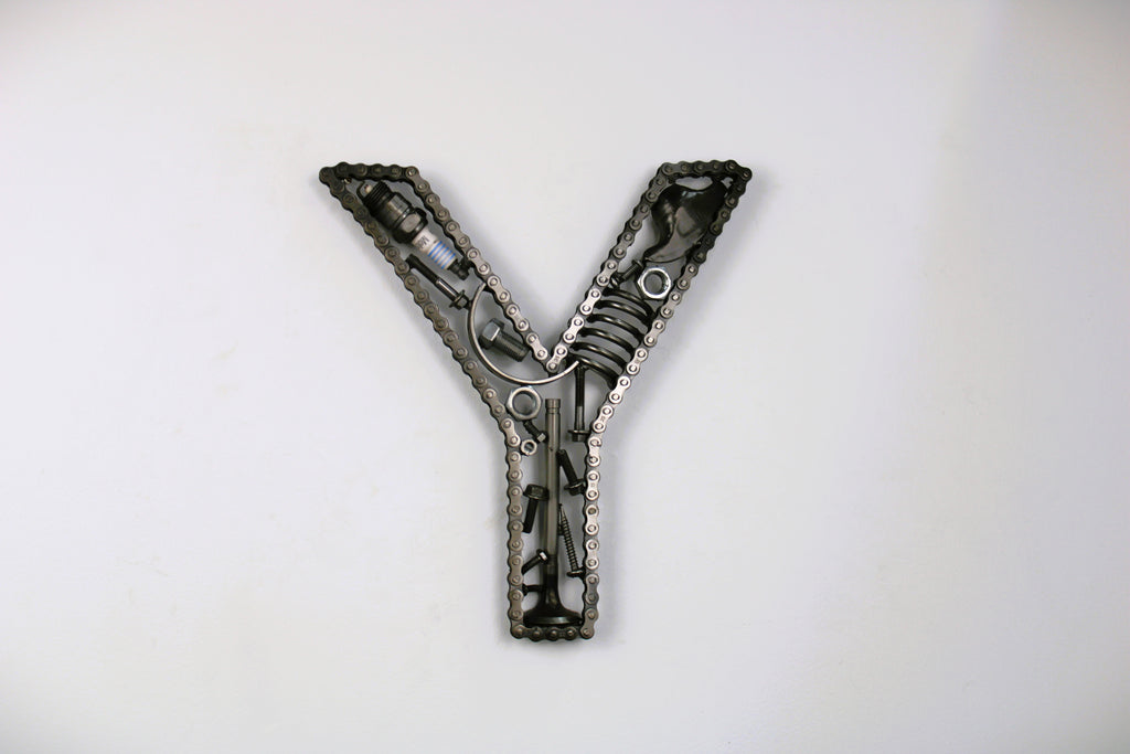 A letter Y made out of real car parts, outlined with a timing chain.
