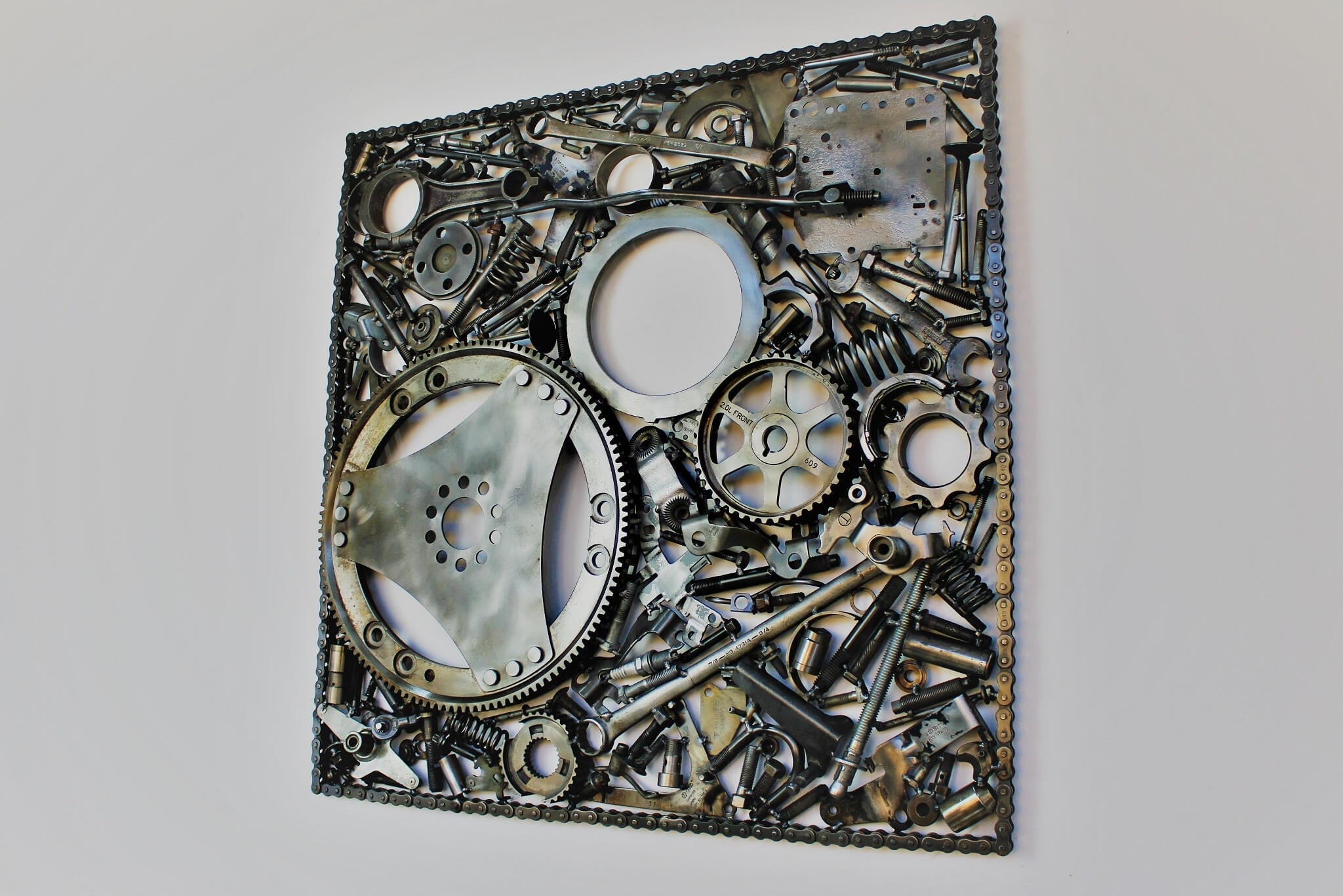 Handcrafted metal wall art piece outlined with timing chain and filled in entirely with polished genuine car engine components.