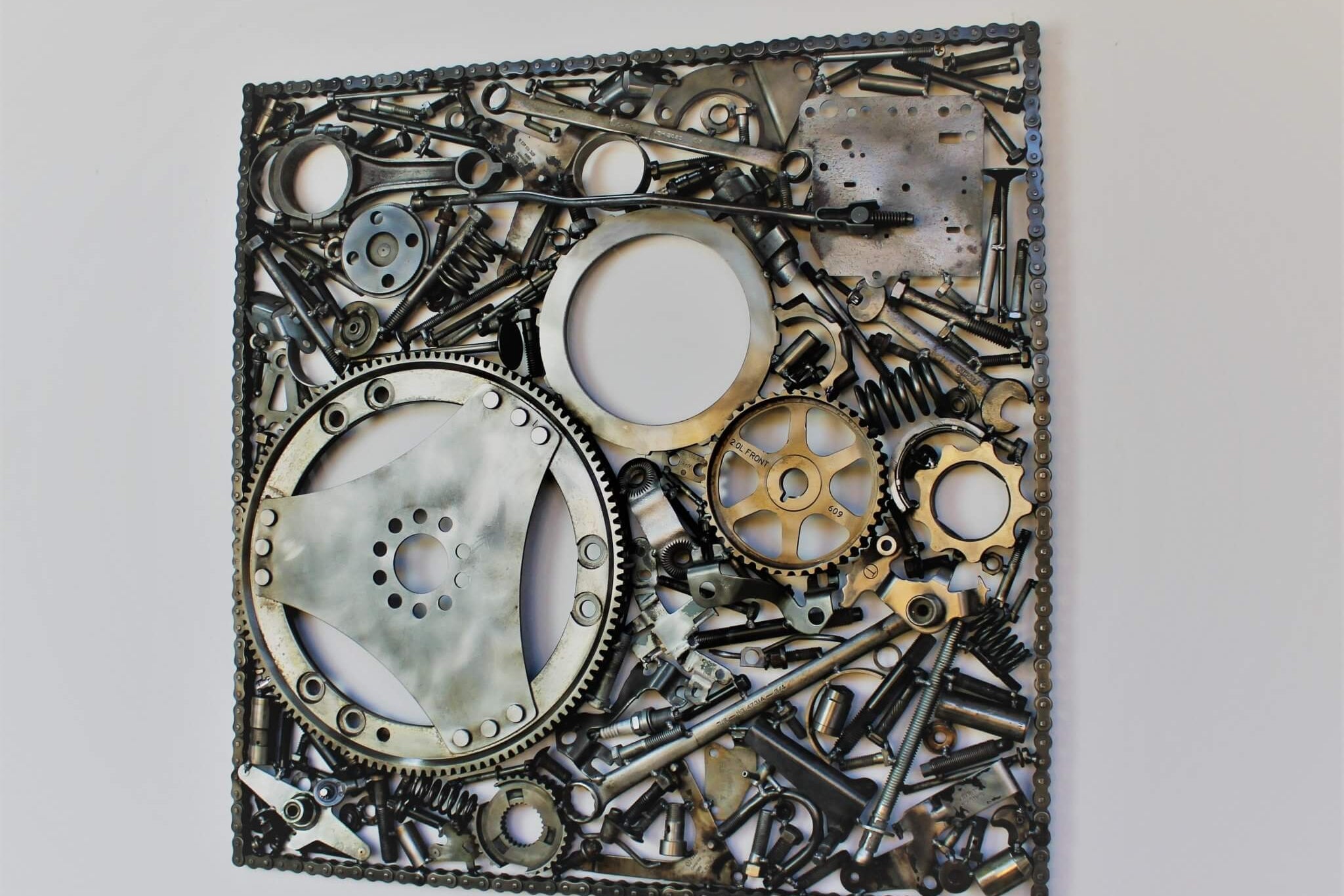 Handcrafted metal wall art piece outlined with timing chain and filled in entirely with polished genuine car engine components.