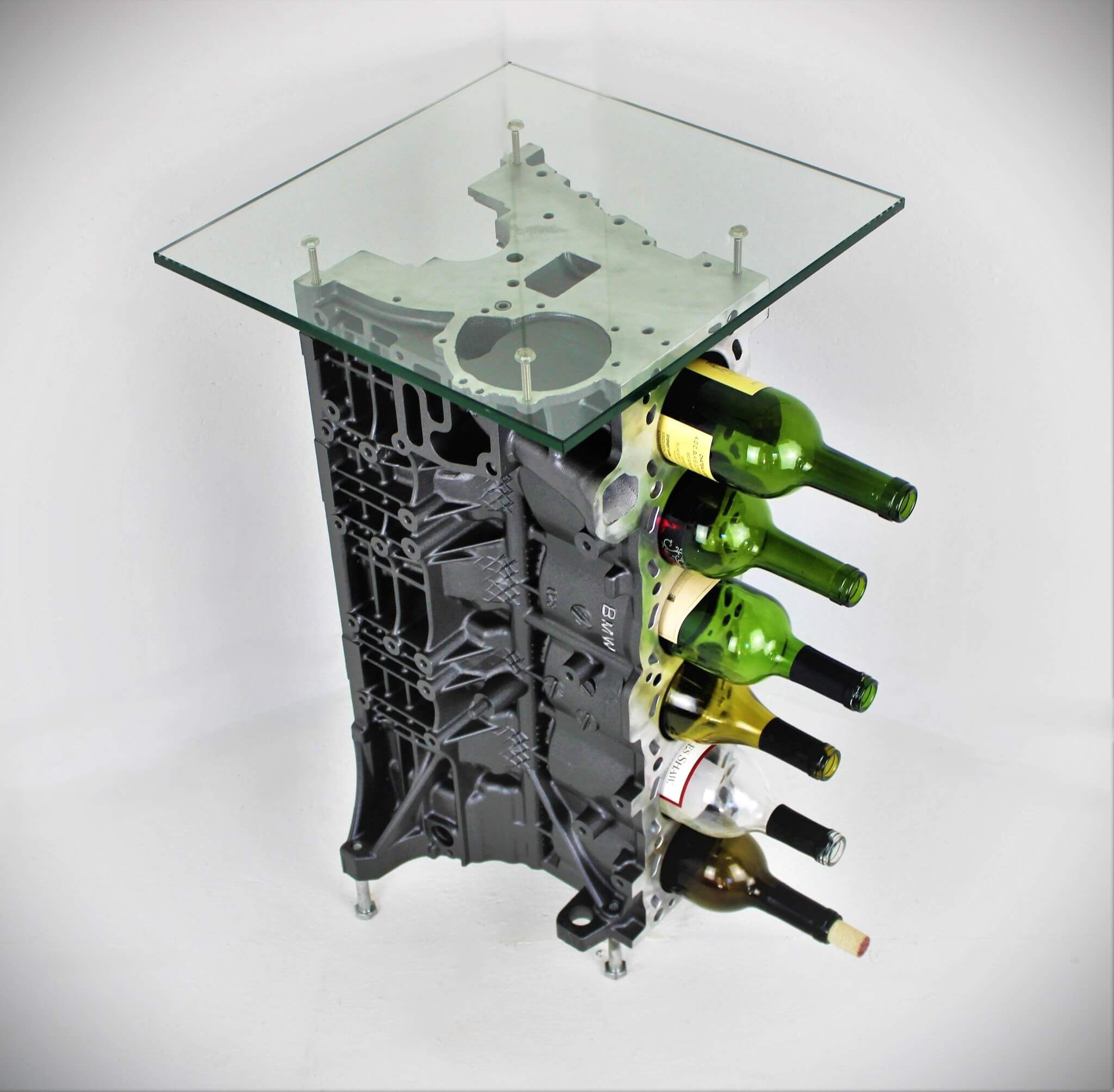 Wine rack table handcrafted from a genuine BMW car engine block finished in gray and silver with a square glass top.