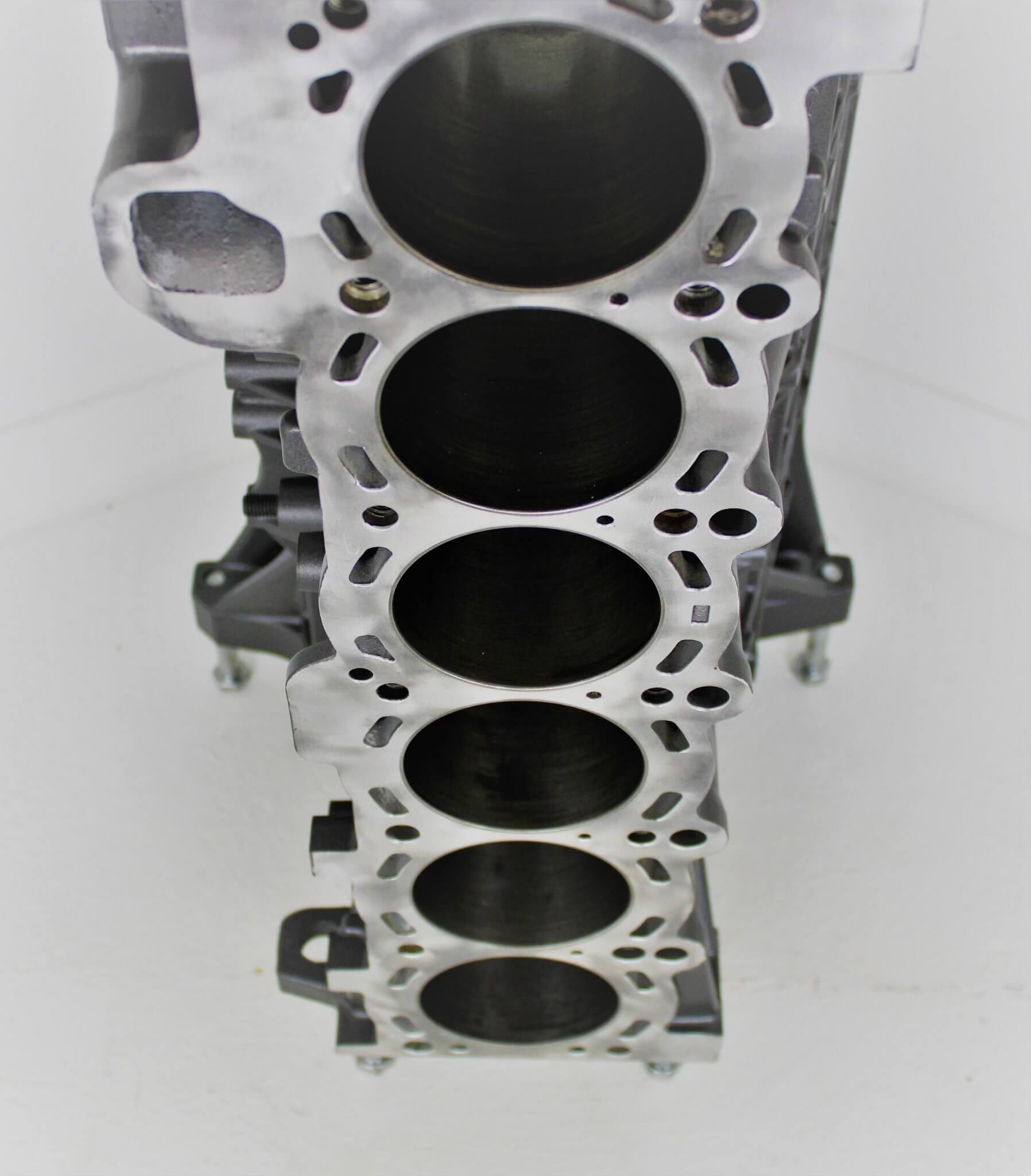 Wine rack table handcrafted from a genuine BMW car engine block finished in gray and silver with a square glass top.