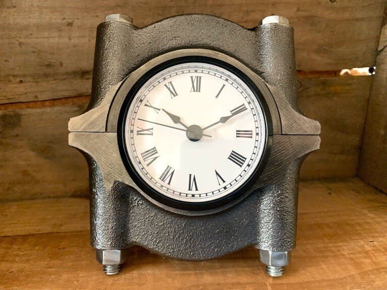 Tabletop clock handcrafted from a genuine polished car engine crankshaft cap with a patina finish and black and white roman numeral clock face.