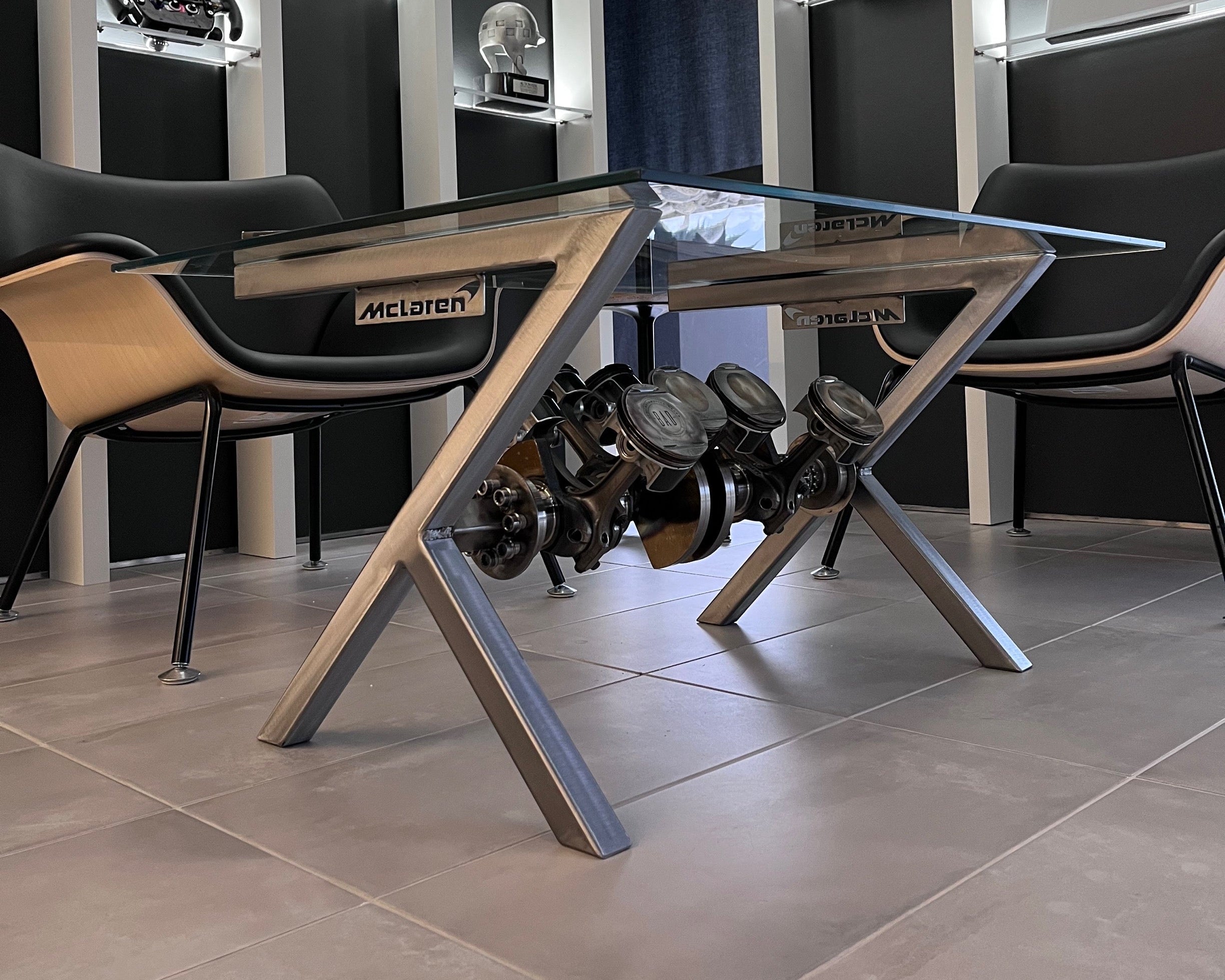 Modern office setup with a glass desk and McLaren logo in a high-tech room.