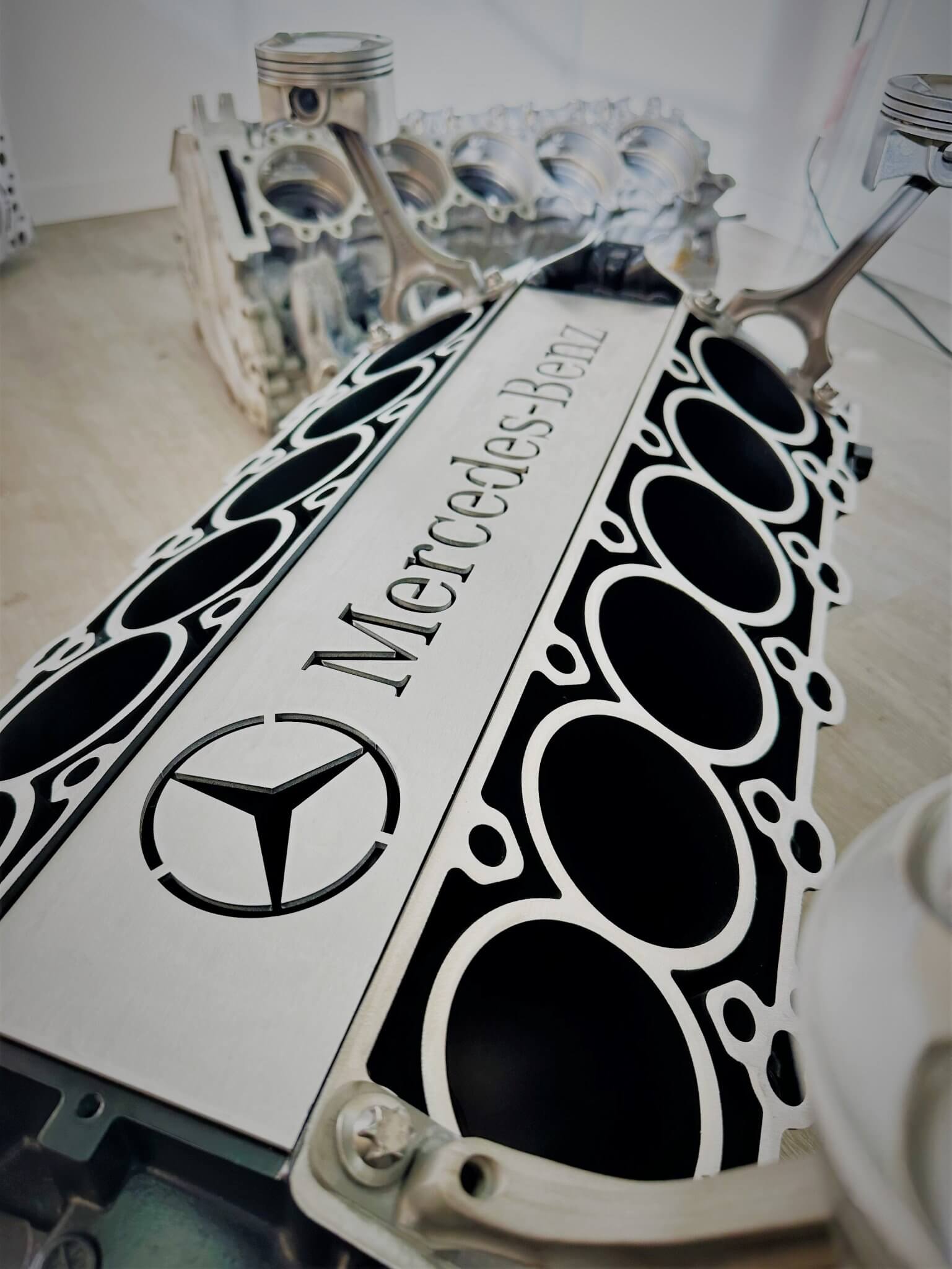 Coffee table handcrafted from a genuine Mercedes V12 car engine, finished in black and silver with the Mercedes-Benz logo displayed and a rectangular glass top.