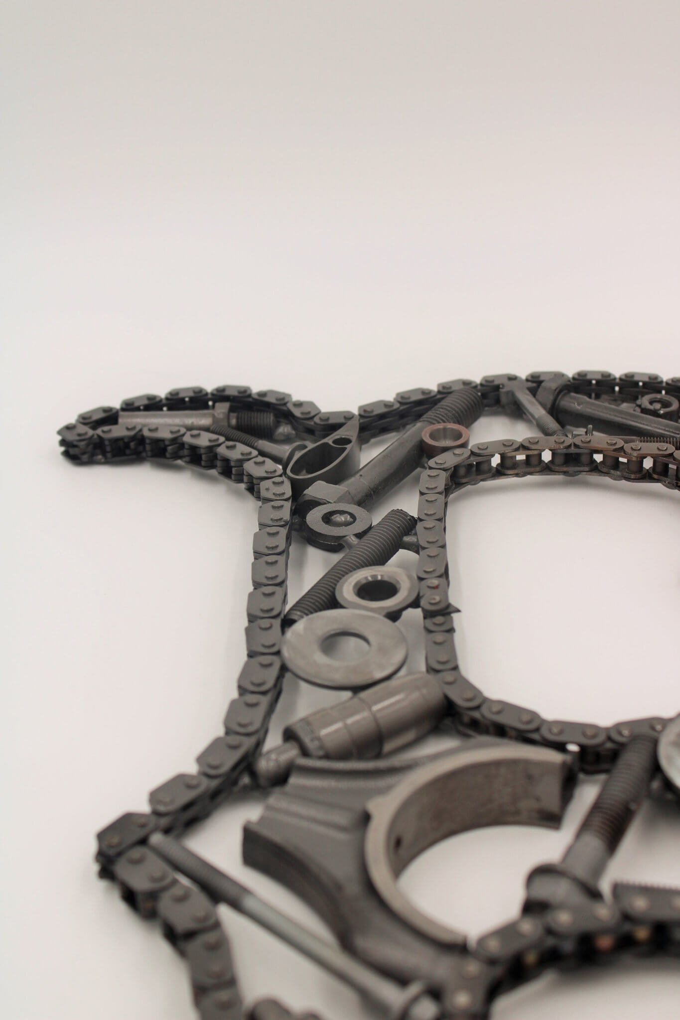 Hand-welded letter monogram decorations outlined with timing chain and filled in entirely with genuine polished car engine components with a glossy finish.