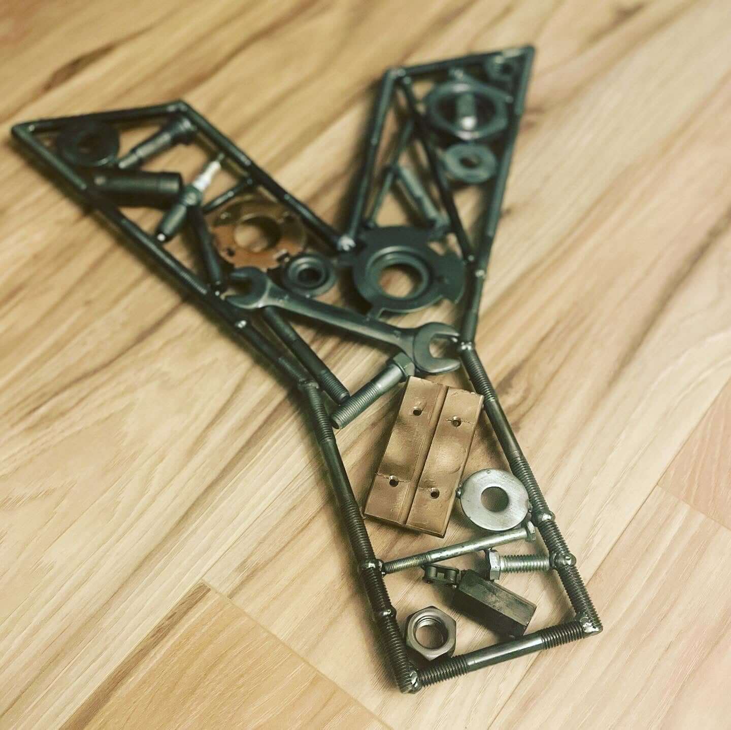 Hand-welded letter monogram decorations outlined with timing chain and filled in entirely with genuine polished car engine components with a glossy finish.