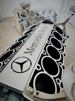 Load image into Gallery viewer, Close-up view of the Mercedes Benz logo displayed in the center of a Mercedes V12 engine block coffee table, finished in black and silver.
