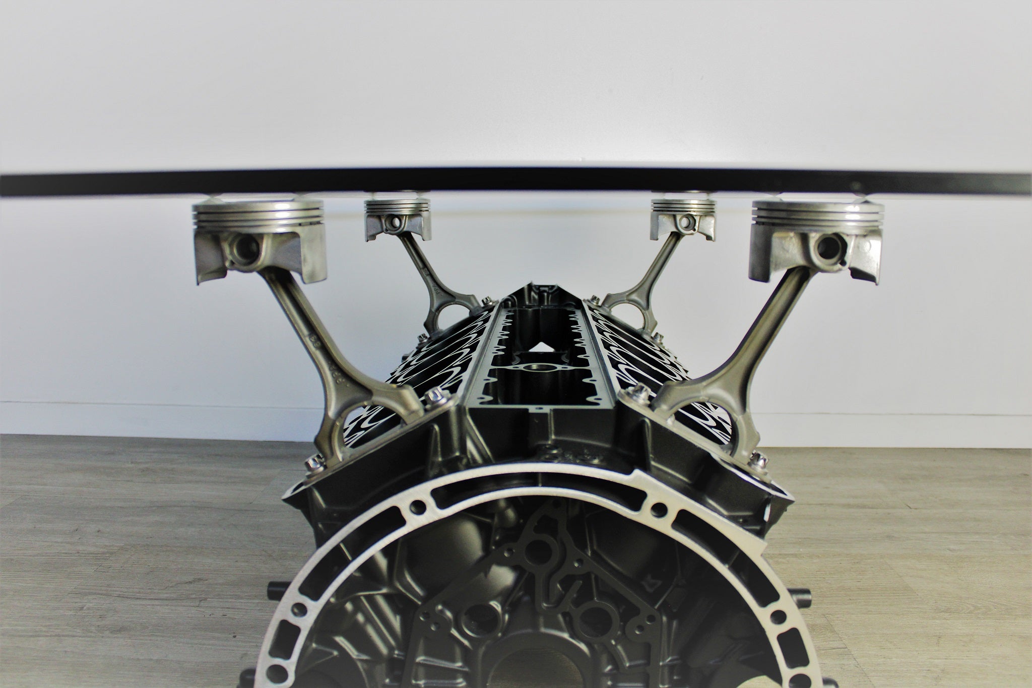 Close-up view of a Mercedes V12 engine block coffee table, finished in black and silver with a rectangular glass top.