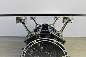 Close-up view of a Mercedes V12 engine block coffee table, finished in black and silver with a rectangular glass top.