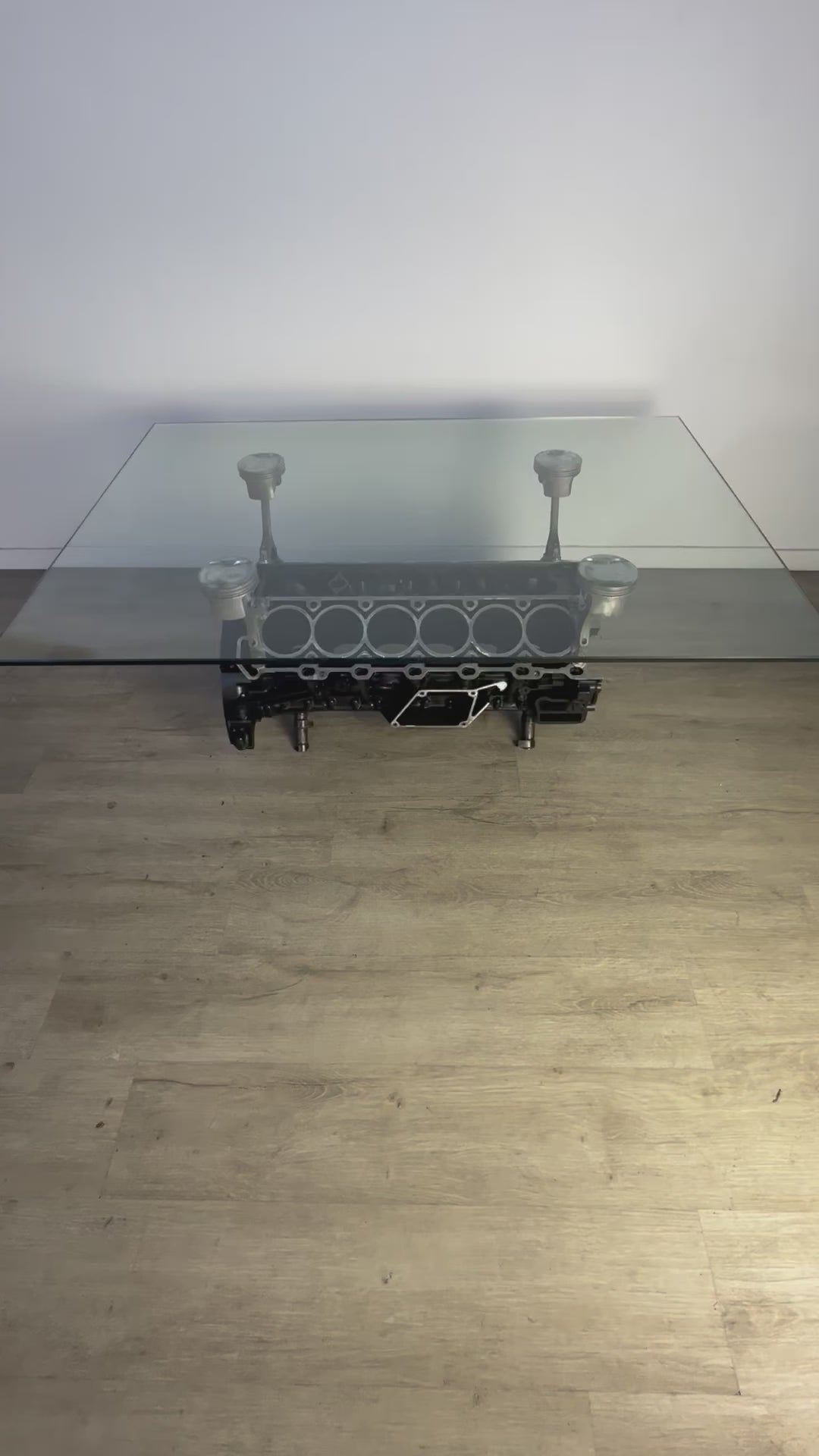 Video of a Mercedes V12 engine block coffee table, finished in black and silver with a rectangular glass top.
