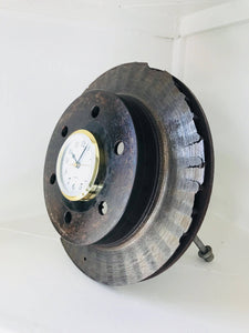 Desk clock made out of a car's brake disk in a patina finish with a gold clock ring.