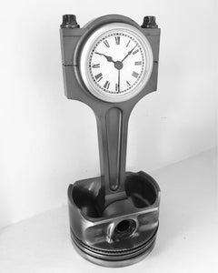 Clock made out of a car engine's piston finished in gunmetal gray with a silver clock ring.