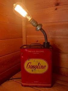 Lamp made out of a red and yellow vintage gas can with a lit incandescent lightbulb.