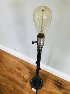 Silver lamp made out of a car's camshaft with out its shade.