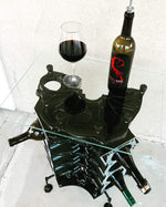 Load image into Gallery viewer, Birds-eye view of an engine block wine rack finished in black with a square glass top, wine bottles stored in its side and a wine bottle and glass on top.
