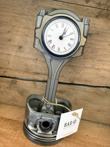 Clock made out of a car engine's piston finished in gunmetal gray with a black clock ring.