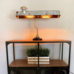 Load image into Gallery viewer, Desk lamp made out of a car&#39;s valve cover lit on top of an entryway table.
