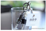 Load image into Gallery viewer, A bottle opener and wine stopper in a glass, both made out of car spark plugs.

