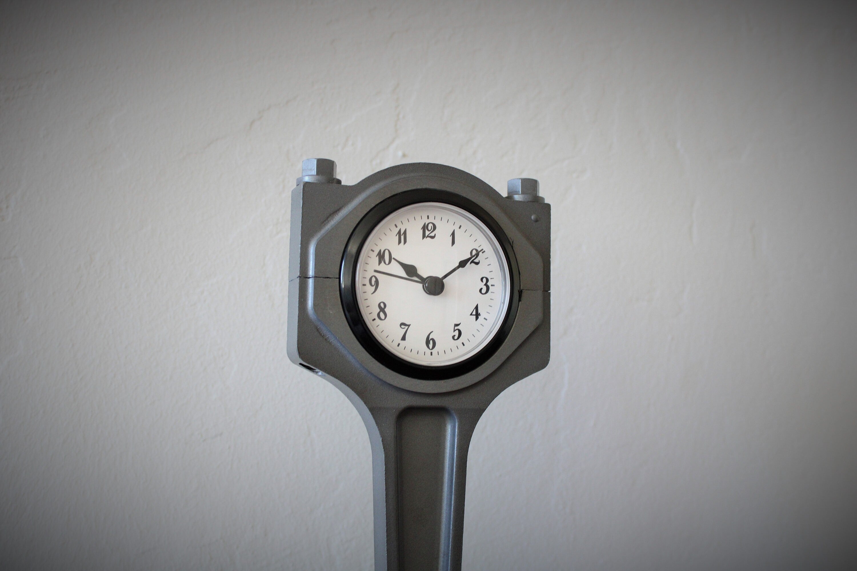Close-up view of a piston clock made out of a Jaguar car's piston, finished in gunmetal gray.