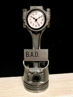 Load image into Gallery viewer, Clock made out of a car engine piston with a custom plaque, reading &quot;B.A.D., Ben&#39;s Automotive Decor&quot;.
