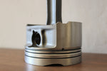 Load image into Gallery viewer, Close-up view of the base of a clock made out of a car engine&#39;s piston, finished in gunmetal gray.
