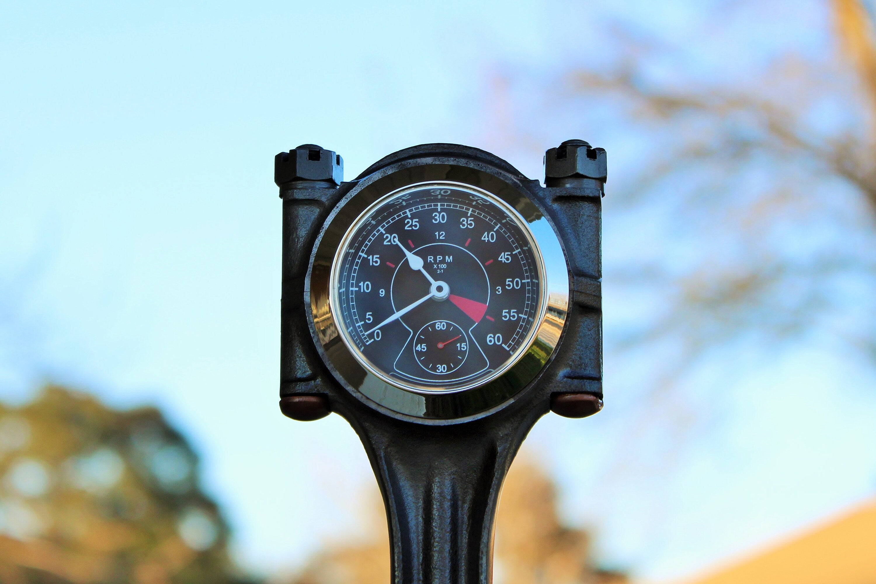 Close-up view of a piston clock made out of a Jaguar E-type XKE car piston, finished in gunmetal gray with a silver clock ring.