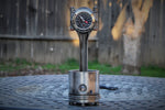 Load image into Gallery viewer, A piston clock made out of a Jaguar E-type XKE car piston, finished in gunmetal gray with a silver clock ring.
