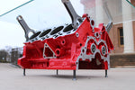 Load image into Gallery viewer, Lower view of an engine block coffee table painted red, its rectangular glass top being held up by car engine pistons.
