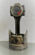 Load image into Gallery viewer, A car piston clock in a patina finish with a gold clock ring and black and red RPM clock face.
