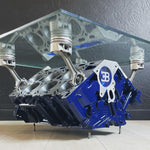 Load image into Gallery viewer, Engine block coffee table painted blue, with its square glass top being held up by car engine pistons.

