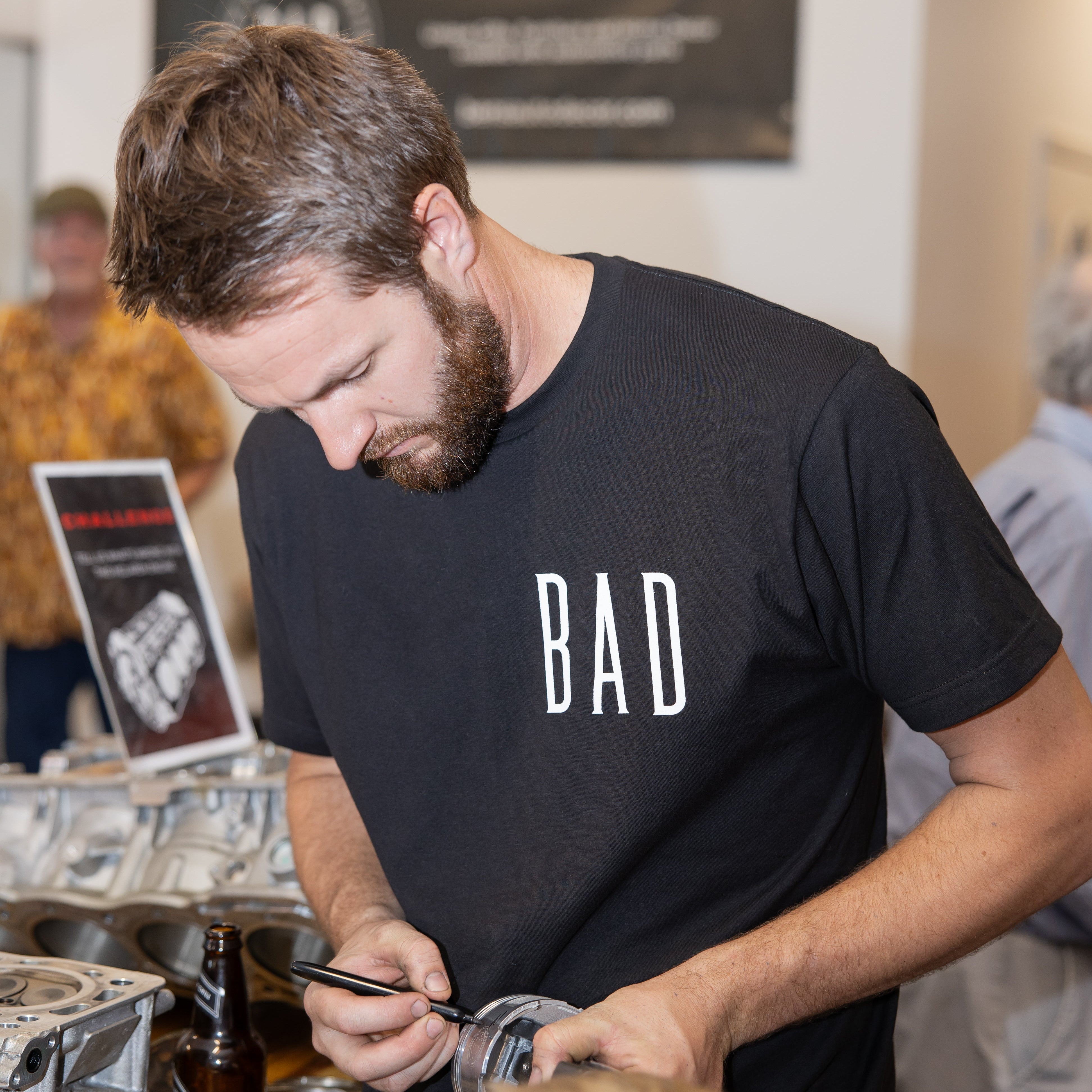 Man in a black 'BAD' t-shirt working at a bar.