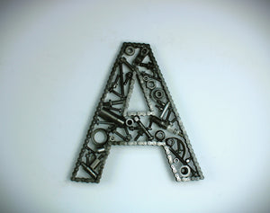 A letter A made out of real car parts, outlined with a timing chain.