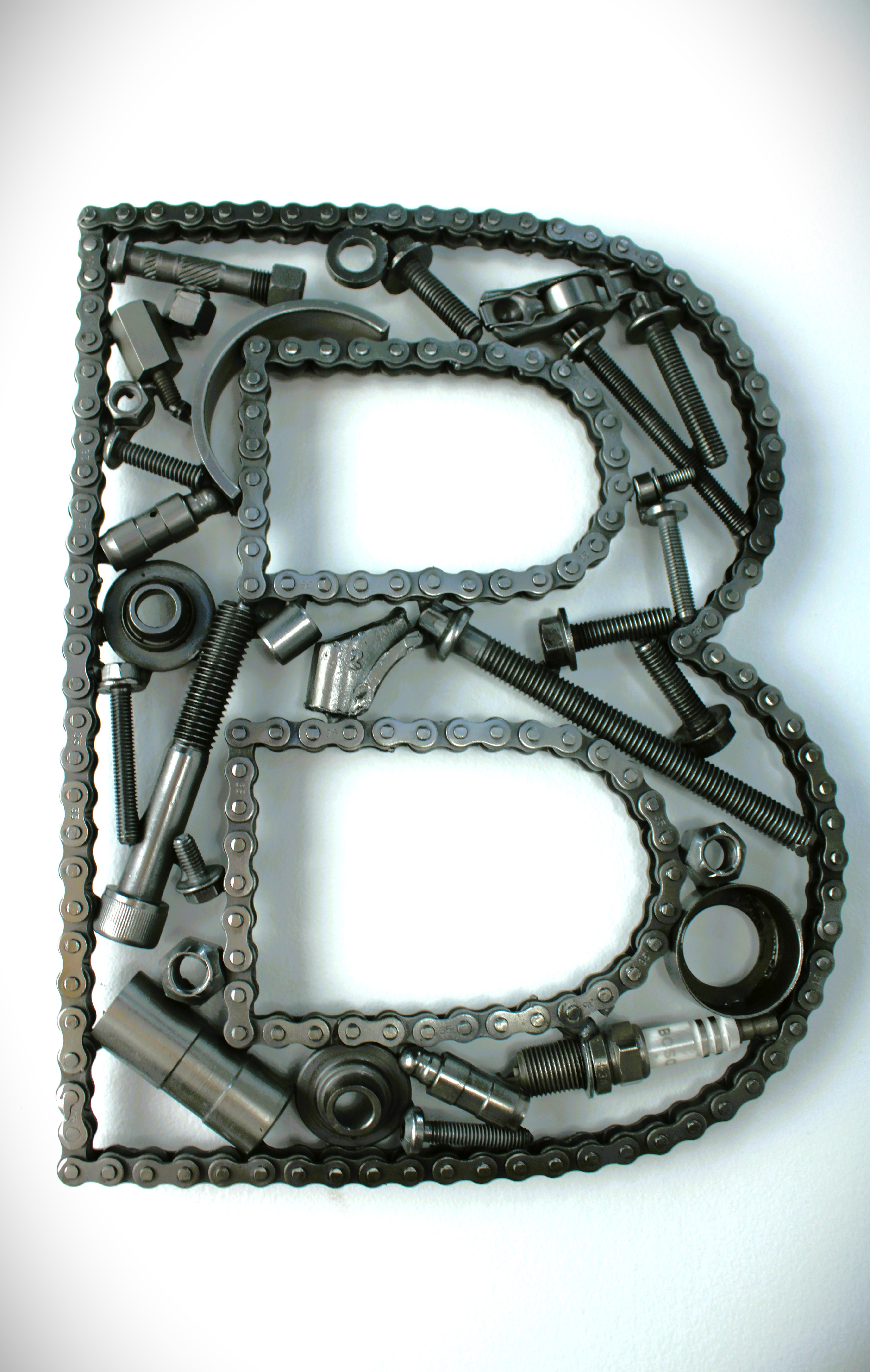 A letter B made out of real car parts, outlined with a timing chain.