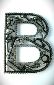 A letter B made out of real car parts, outlined with a timing chain.