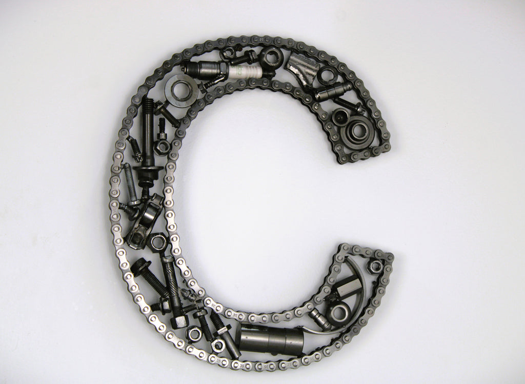 A letter C made out of real car parts, outlined with a timing chain.