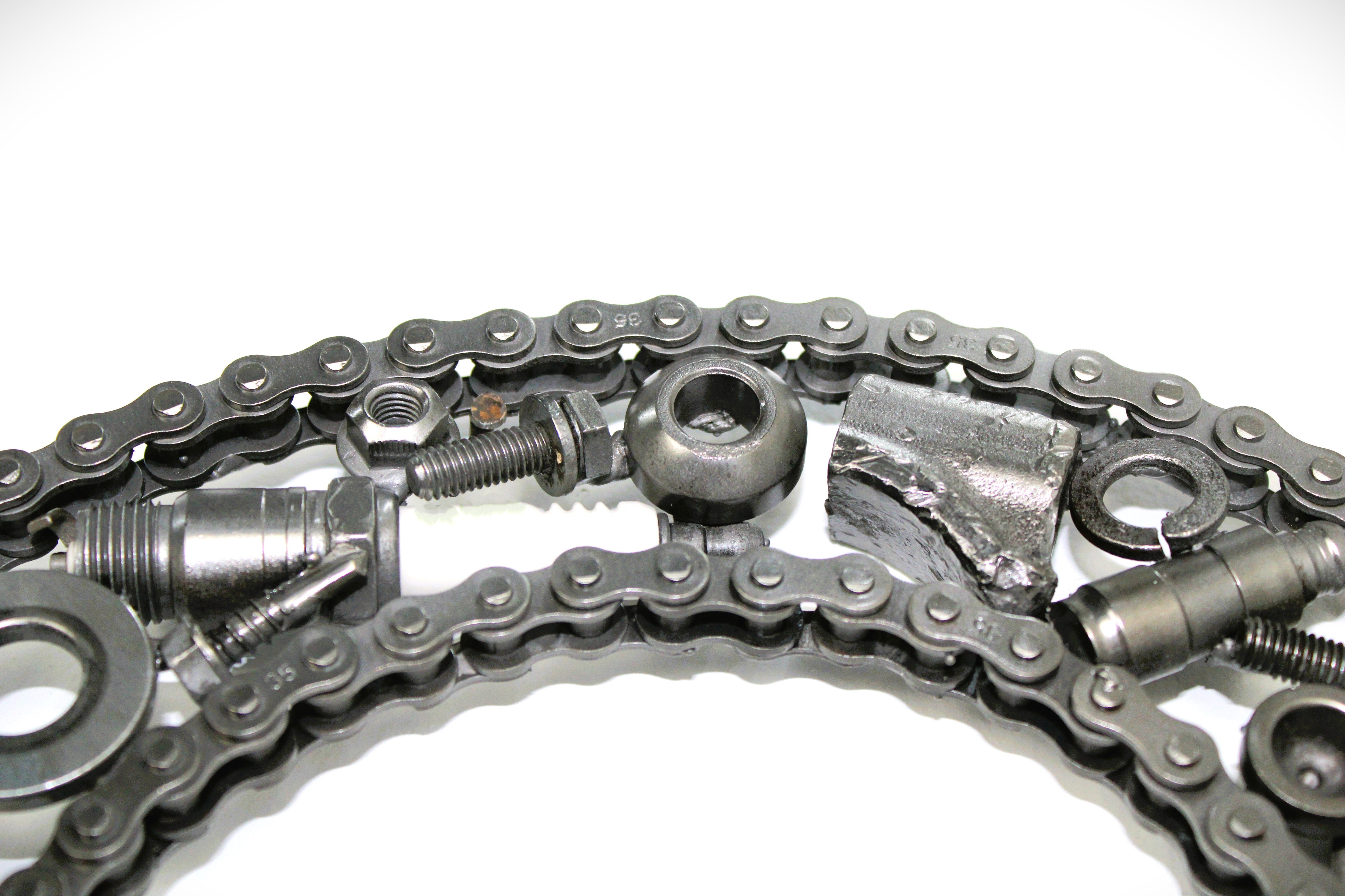 Close-up view of a letter C made out of real car parts, outlined with a timing chain.