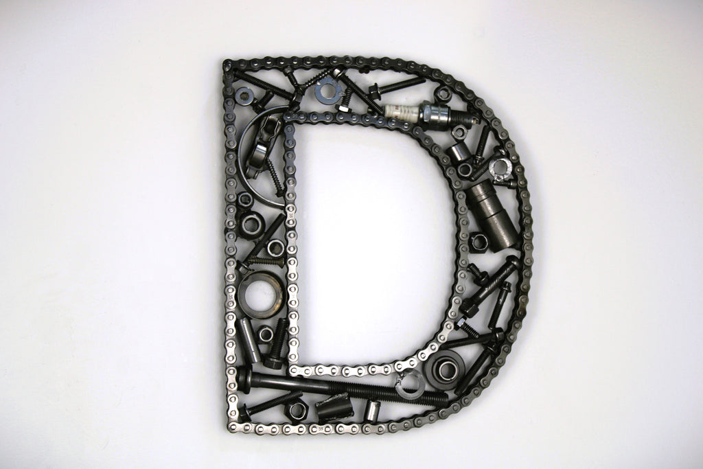 A letter D made out of real car parts, outlined with a timing chain.