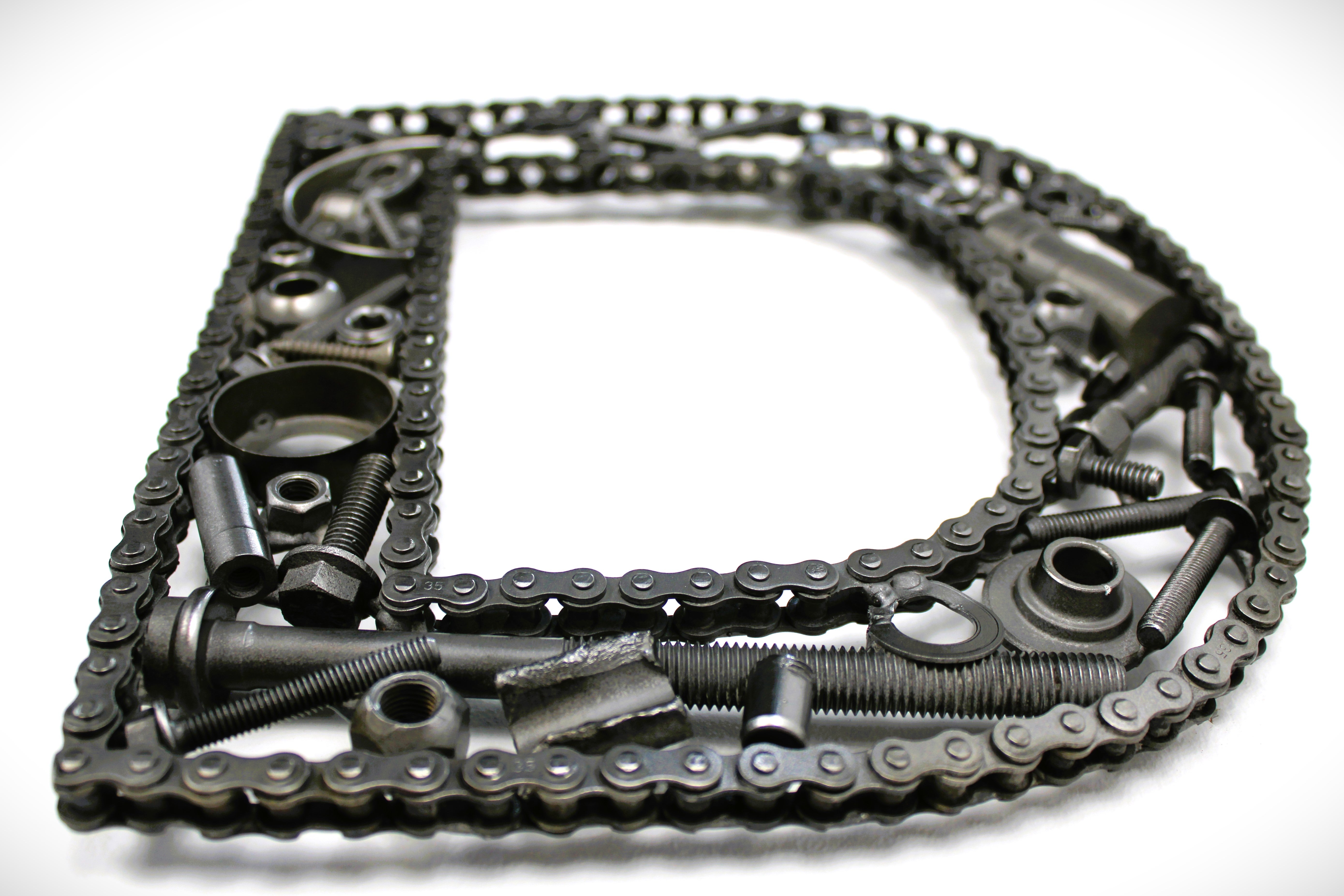 Close-up view of a letter D made out of real car parts, outlined with a timing chain.