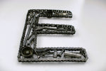 Load image into Gallery viewer, A letter E made out of real car parts, outlined with a timing chain.

