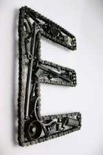 Load image into Gallery viewer, A letter E made out of real car parts, outlined with a timing chain.
