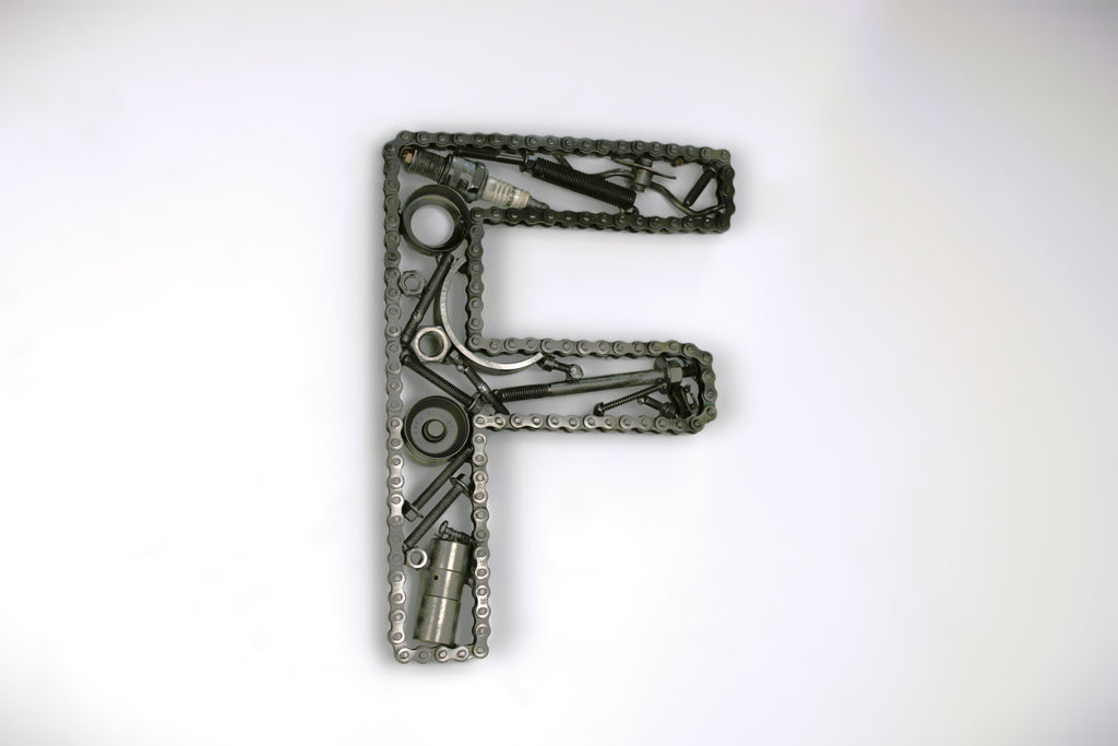 A letter F made out of real car parts, outlined with a timing chain.