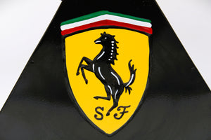 Close-up of the Ferrari logo on a black and yellow painted gas can.