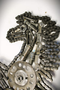 Close-up view of a Ferrari prancing horse logo art piece, made out of car parts and outlined with a timing chain.