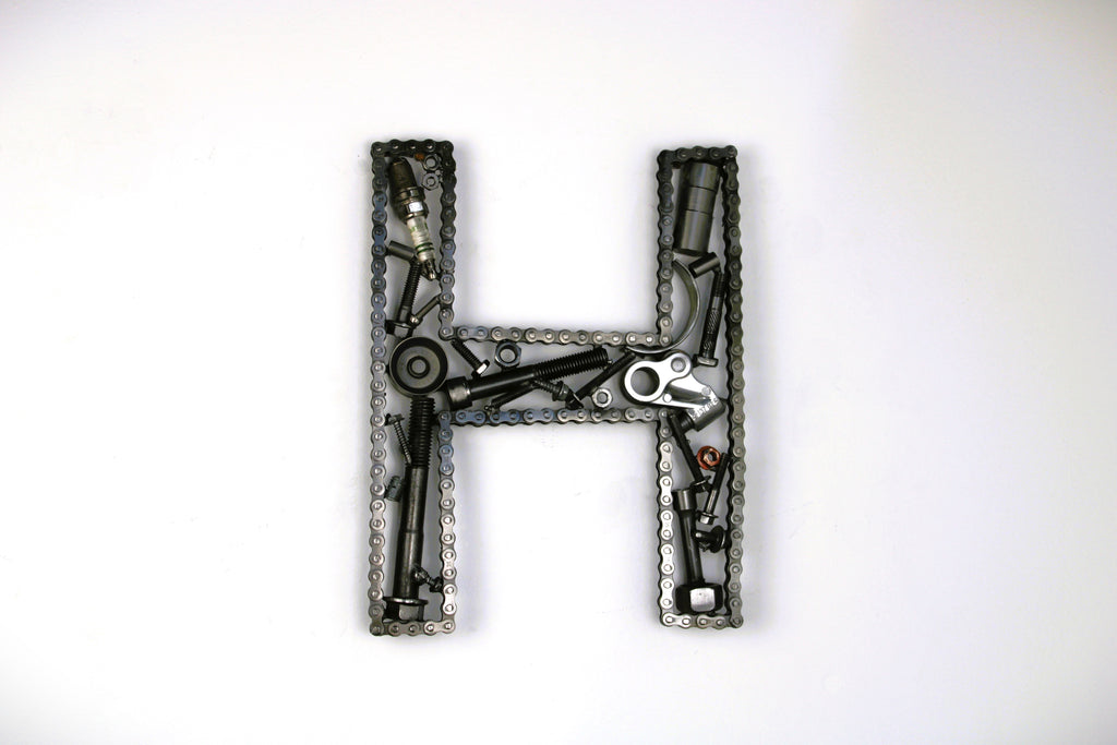 A letter H made out of real car parts, outlined with a timing chain.