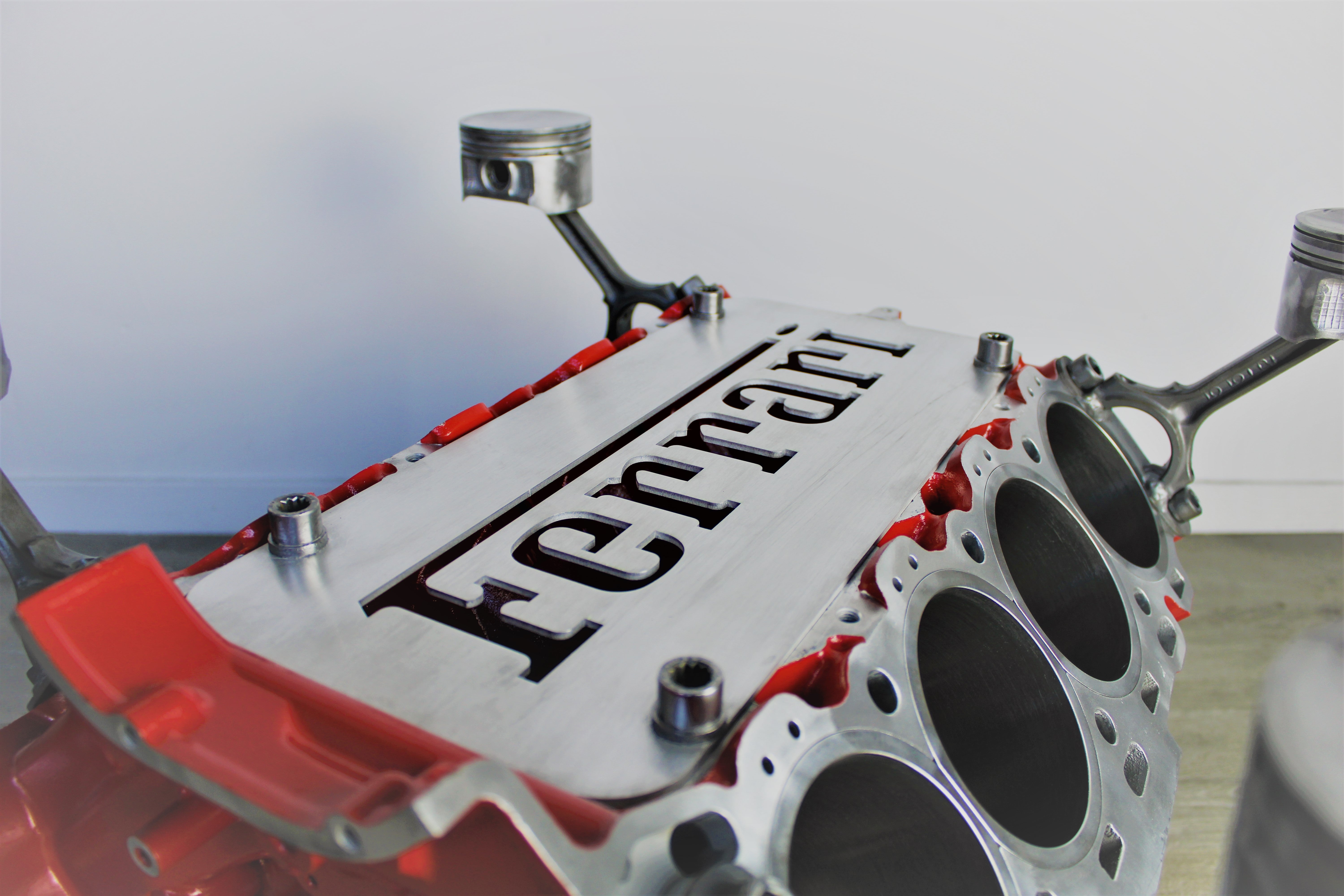 Close-up view of the Ferrari logo displayed on a Ferrari engine block coffee table finished in red without its glass top.