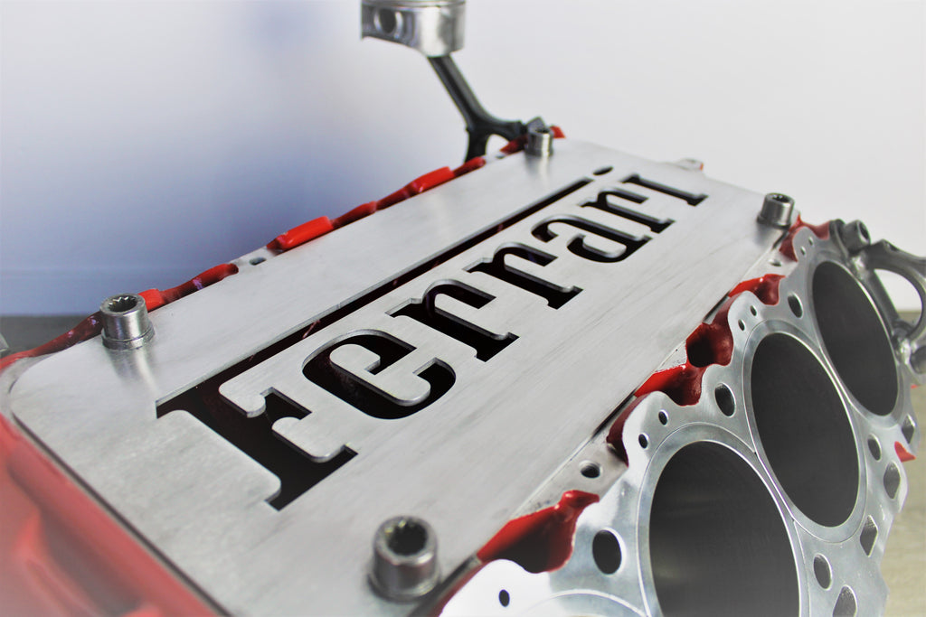 Close-up view of a Ferrari engine block coffee table finished in red without its glass top, the Ferrari logo displayed in the center.