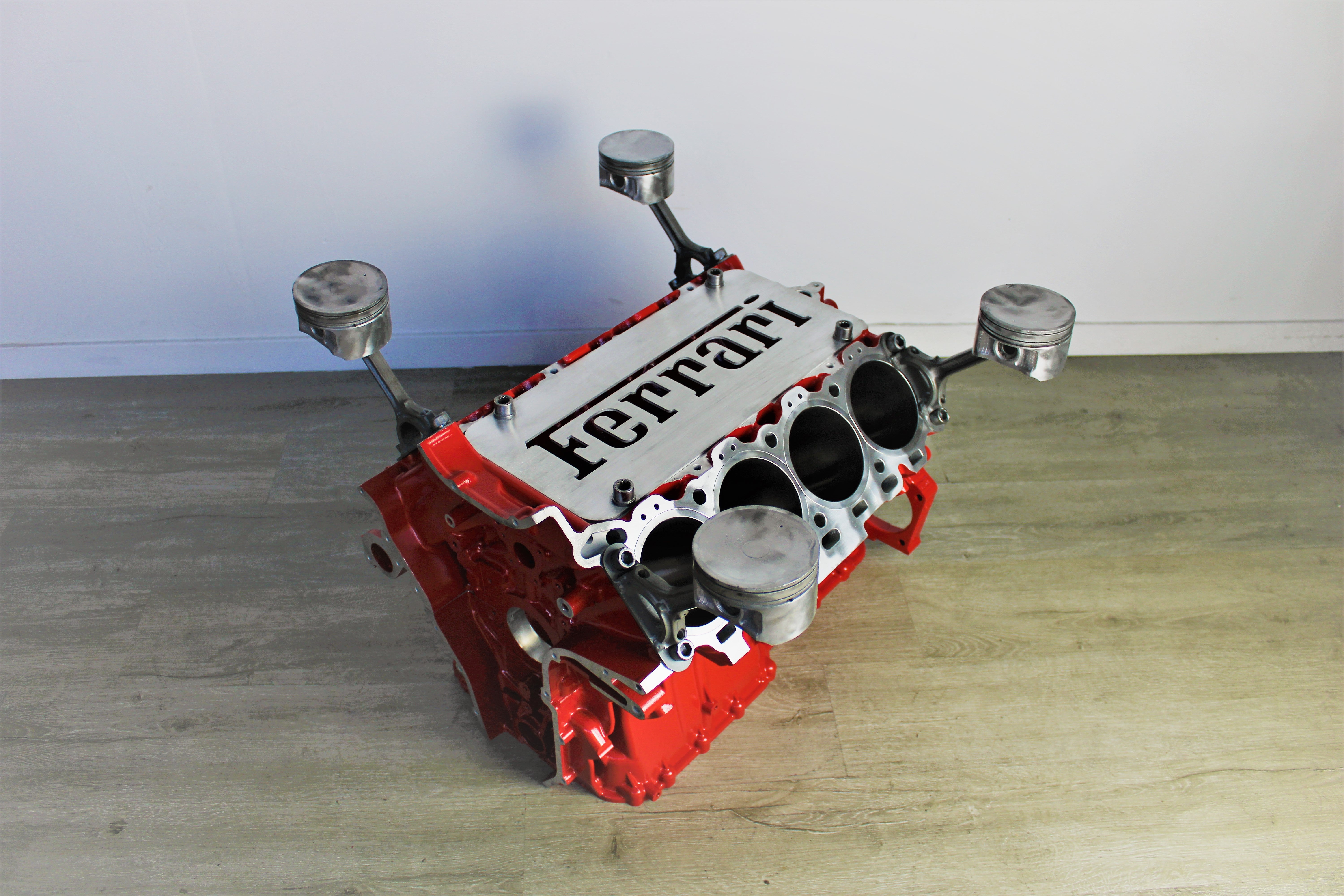 Ferrari engine block coffee table finished in red without its glass top and the Ferrari logo displayed in the center.